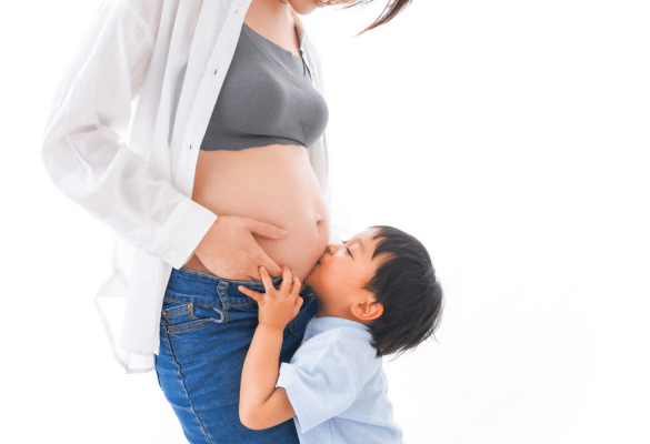 Femme enceinte avec un enfant posant la main sur son ventre au cinquième mois de grossesse