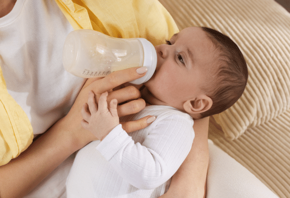 bébé buvant un biberon illustrant l’impact du lait infantile sur les selles