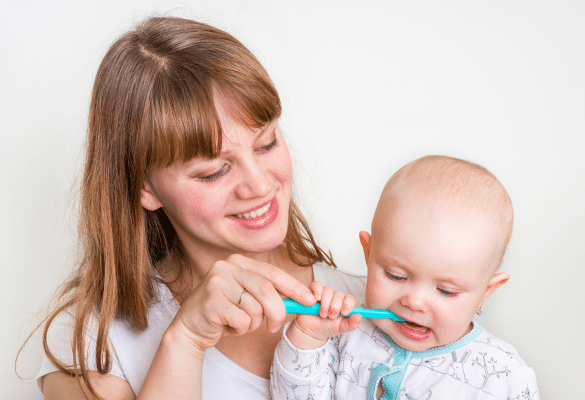 parent qui brosse les dents de bébé avec une brosse à dents adaptée