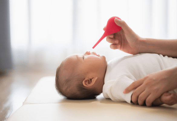 parent administrant du sérum physiologique dans le nez d’un bébé