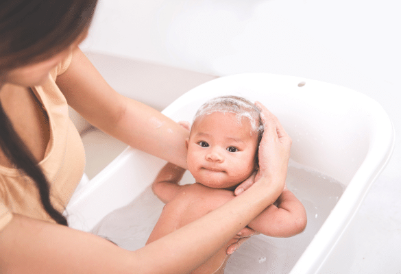 Nourrisson installé dans une baignoire bébé sécurisée, soutenu par un parent attentif.