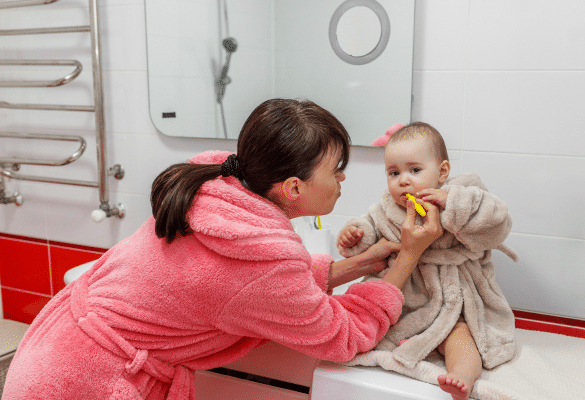 parent qui brosse les dents de bébé avec une brosse à dents pour bébé