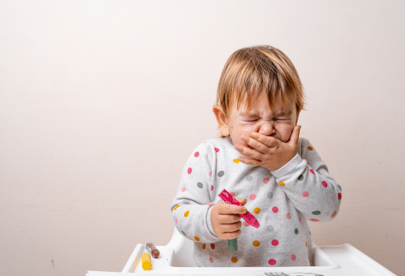 Jeune enfant qui tousse et se sent gêné en mangeant, illustrant l’inhalation possible d’un corps étranger.
