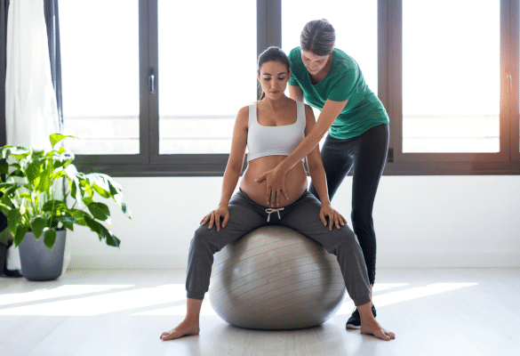 Femme enceinte pratiquant un exercice de préparation à l’accouchement sur ballon pendant le troisième trimestre de grossesse.