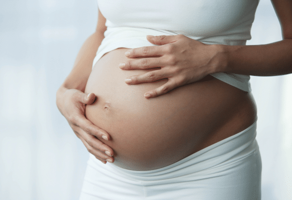 Femme enceinte caressant son ventre rond pendant le troisième trimestre de grossesse