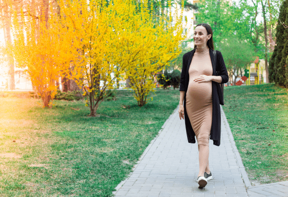 Femme enceinte marchant dans un parc pendant sa grossesse