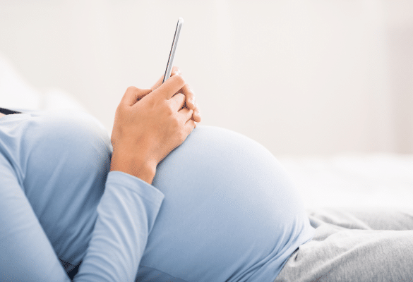 femme enceinte utilisant un téléphone pour chronométrer des contractions grossesse