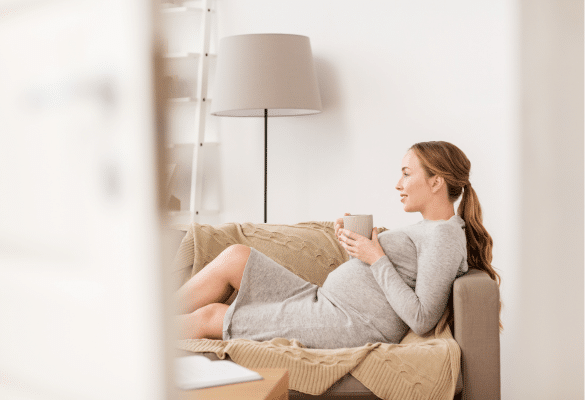 Femme enceinte allongée ressentant une sensation d’humidité pouvant évoquer une fissure de la poche des eaux