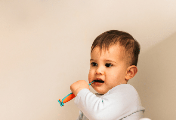 bébé qui tient une brosse à dents et se brosse les dents