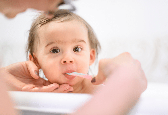 parent nettoie les gencives de bébé avec une compresse humide