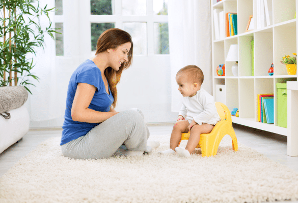 Maman encourageant son enfant assis sur un petit pot jaune, illustrant la bienveillance et la complicité dans l’apprentissage de la propreté.