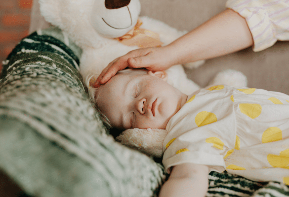 Enfant endormi paisiblement dans son lit avec un doudou, illustrant les routines nocturnes pendant l’apprentissage de la propreté.