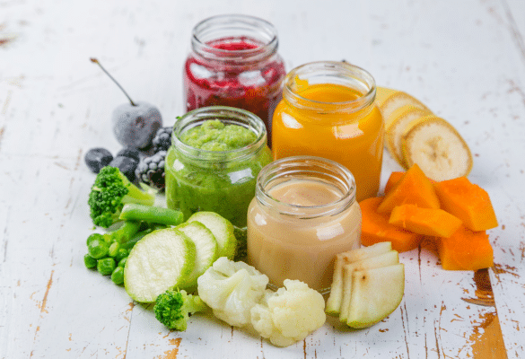 Purées colorées de légumes (carotte, courgette, patate douce) dans de petits bols avec cuillères pour bébé