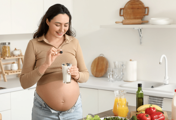 femme enceinte souriante touchant son ventre en cuisine. Au début de la grossesse, beaucoup de femmes se demandent déjà si ce sera une fille ou un garçon.