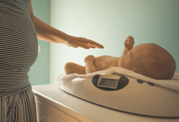 Parent qui pèse son bébé à la maison sur une balance électronique pour suivre son poids moyen.