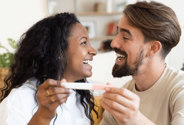 Future maman offrant un test de grossesse dans une boîte cadeau au futur papa, à la maison