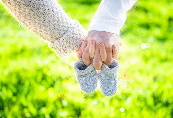 Couple tenant une paire de chaussons de bébé dans un décor lumineux et naturel