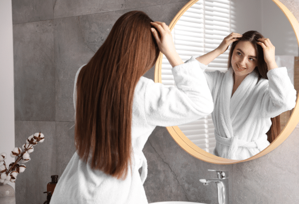 Jeune femme dans sa salle de bain, regardant ses cheveux quelques jours après son accouchement.