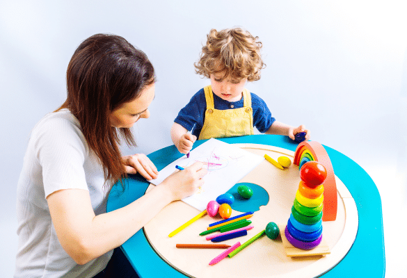 Activité petite enfance avec enfant manipulant du matériel créatif accompagné d’un adulte