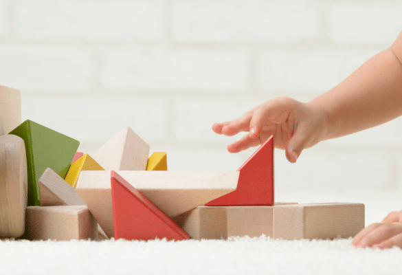 Main d’un bébé utilisant la pince pouce index pour saisir un petit objet