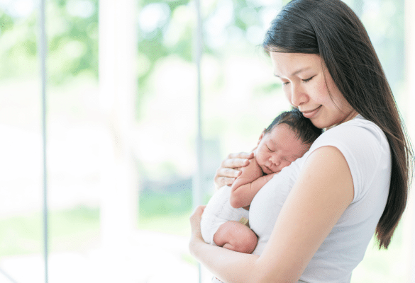 Maman tenant son bébé dans ses bras, sourire discret, atmosphère apaisante