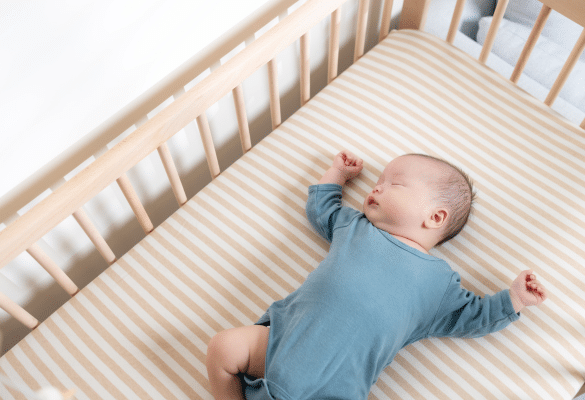Bébé dormant paisiblement dans son lit pendant la sieste de l’après-midi, illustrant un sommeil réparateur et un environnement apaisant.