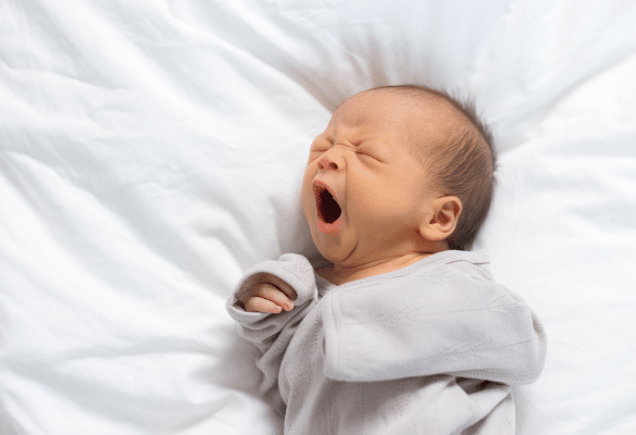 Parent observant son bébé qui se frotte les yeux, illustrant les signes de fatigue à repérer avant la sieste.