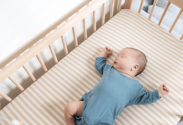 Bébé allongé sur le dos dans son lit à barreaux