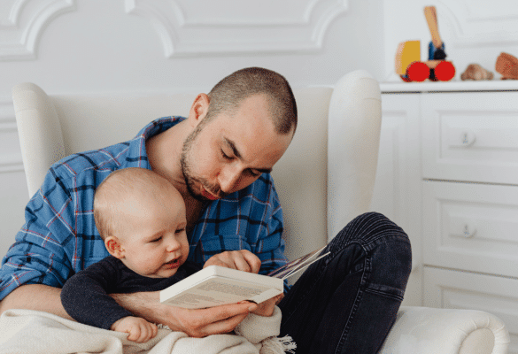 Papa lisant une histoire à son bébé installé sur ses genoux avant le coucher