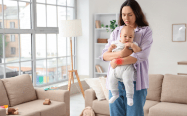 Jeune maman tenant son poignet avec une expression d’inconfort dans un intérieur lumineux