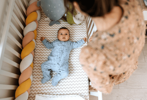 Parent près de son bébé éveillé dans son lit au moment du coucher