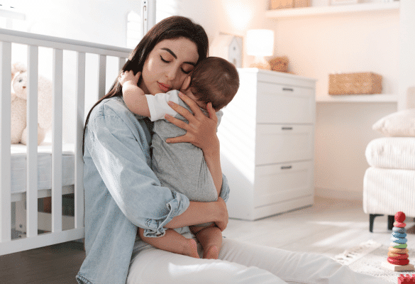 Mère tenant son bébé contre elle dans une chambre