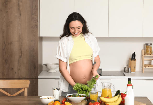 Femme enceinte préparant une salade et des aliments frais dans sa cuisine