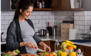 Femme enceinte préparant un repas équilibré avec fruits et légumes pendant la grossesse