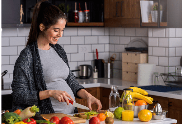Femme enceinte préparant un repas équilibré avec fruits et légumes pendant la grossesse