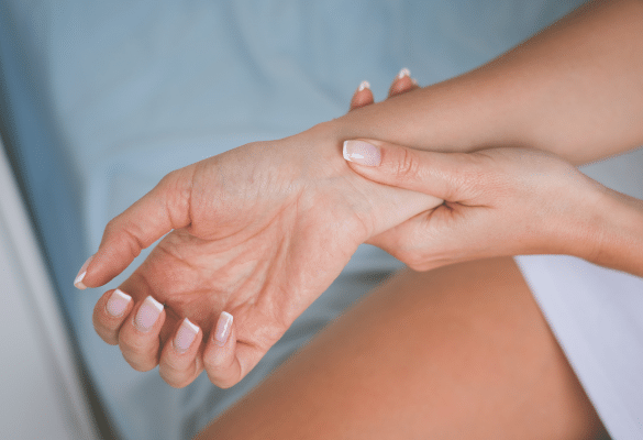 Femme enceinte massant doucement son poignet pour soulager la douleur du canal carpien pendant la grossesse.