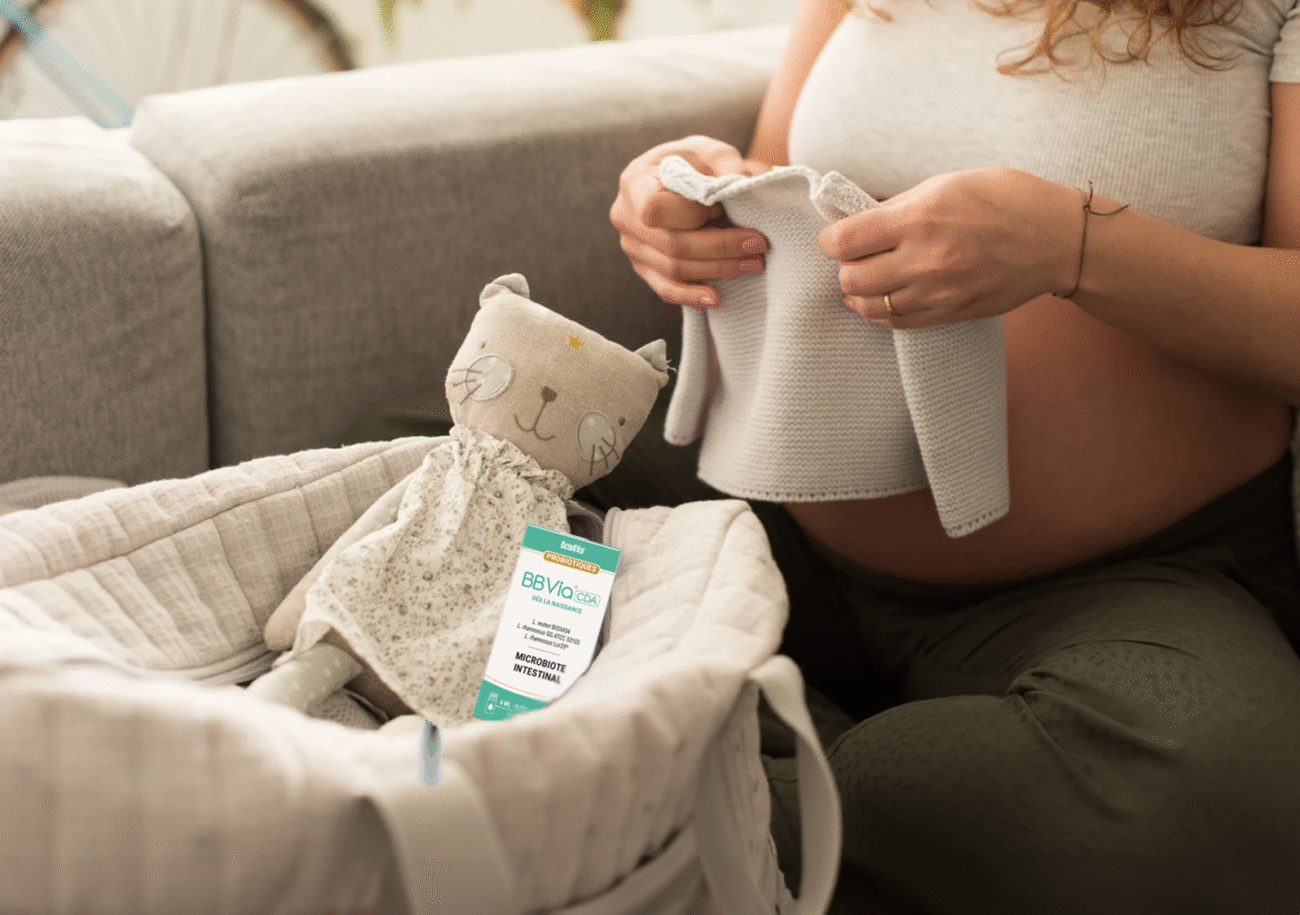 Maman rangeant les affaires de bébé avec un flacon de BBVia® CDA dans un panier, illustrant un geste du quotidien.