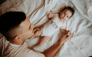père massant doucement son bébé pour créer le lien d’attachement