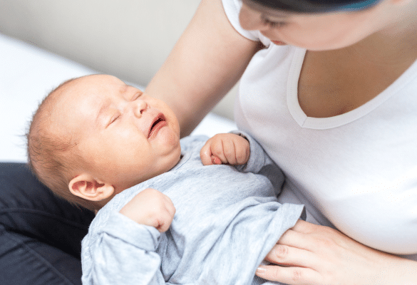 Parent massant doucement le ventre de son bébé pour soulager les coliques