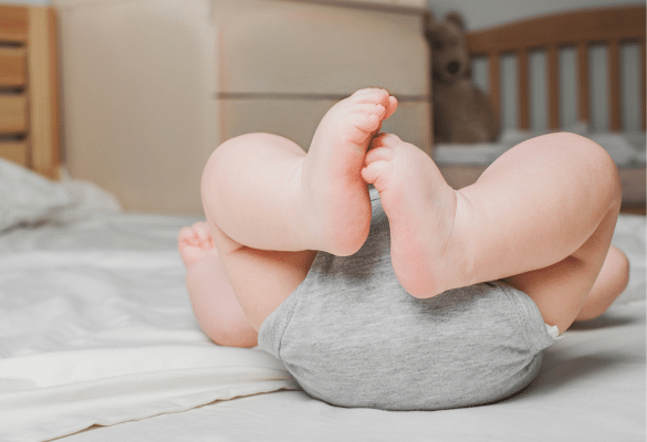 Bébé allongé avec jambes relevées pouvant évoquer des coliques du nourrisson