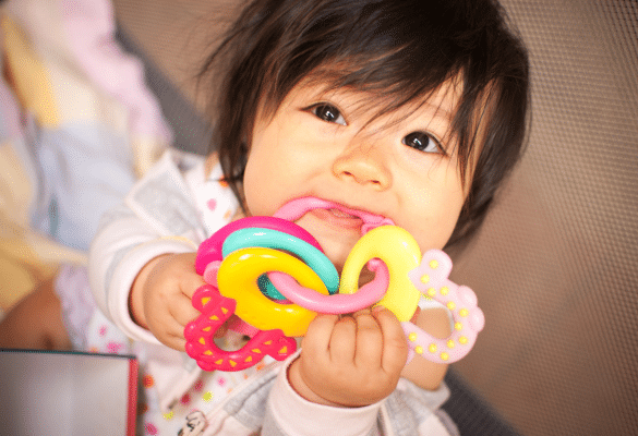 Bébé mordillant un anneau de dentition pour soulager une poussée dentaire