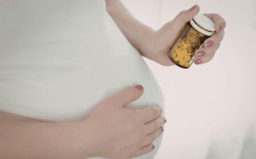 femme enceinte tenant un complément alimentaire grossesse