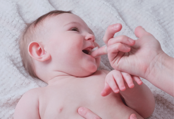 Parent massant les gencives de bébé avec un doigt propre pour soulager une poussée dentaire