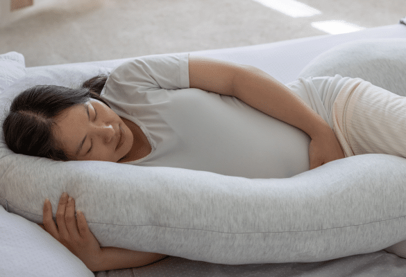 Femme enceinte se reposant avec un coussin de grossesse.
