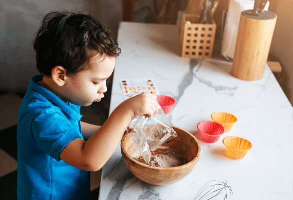 Enfant mélangeant une préparation culinaire dans un saladier pour participer à la cuisine.