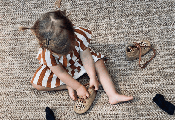 Jeune enfant qui met seul ses chaussures pour développer son autonomie