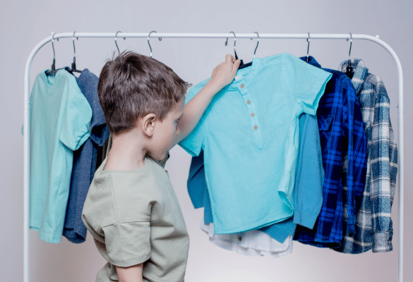 Enfant qui choisit seul des vêtements sur un portant.