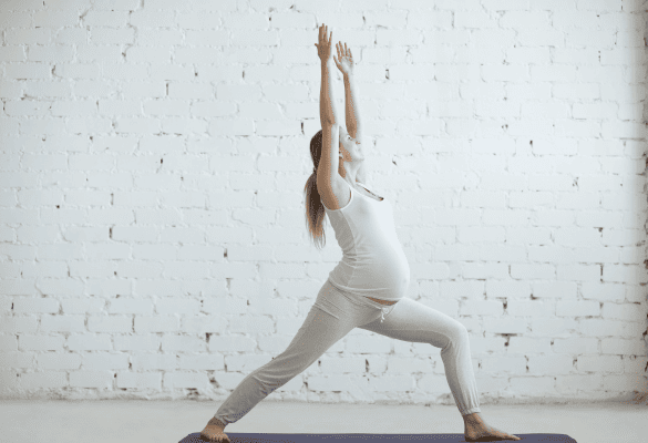 Femme enceinte pratiquant le yoga pré-natal dans une salle lumineuse
